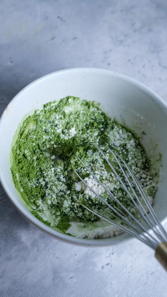 Matcha cake flour, match and oil in bowl with a whisk 