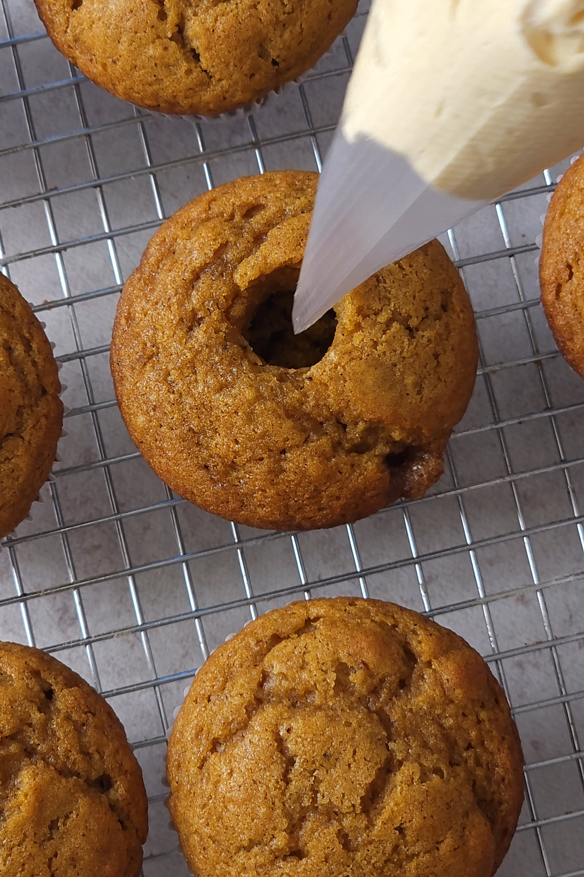 pumpkin cupcake with hole in the middle and piping bag