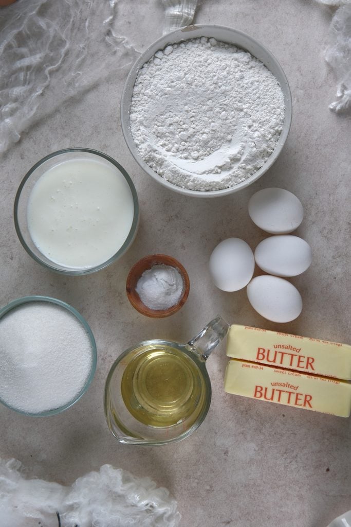 dry ingredients, eggs, butter, oil, buttermilk all laid out with white backdrop